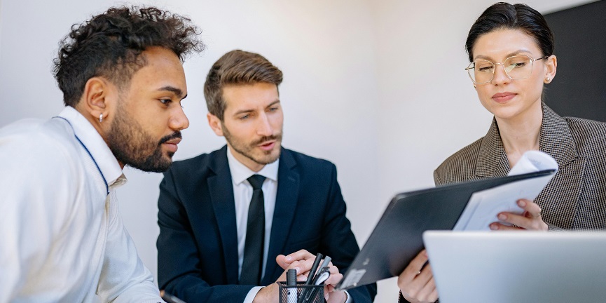 Three Employees sitting and reviewing a page on a clipboard